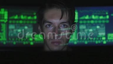 黑客程序员在计算机上工作，而绿色代码字符在网络安全中心反射他的脸